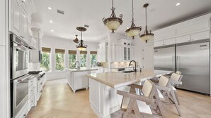Una cocina amplia con armarios blancos, una isla central y un refrigerador de acero inoxidable.