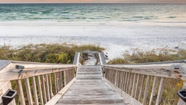 Ein Holzsteg führt zu einem Strand mit Blick auf das Meer.