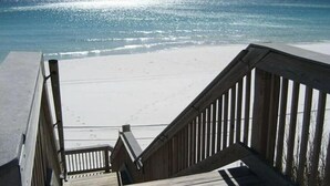 Eine Holztreppe führt zu einem Strand mit freiem Blick auf das Meer.