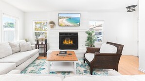 A living room with a fireplace, a sofa, a coffee table, and a chair. - 2-Unit House | Giant Rooftop Deck! | Tons of Living Space | 1 Block to Beach! (Newport Beach)