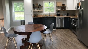 Une cuisine moderne avec une table à manger en bois, des chaises grises et des appareils électroménagers en acier inoxydable.