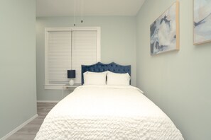 Relax in this serene bedroom with a large bed, window, and nightstand with a lamp.