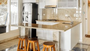 A kitchen with a central island, bar stools, a refrigerator, and a backsplash. - Isla Amor! (Cartagena)