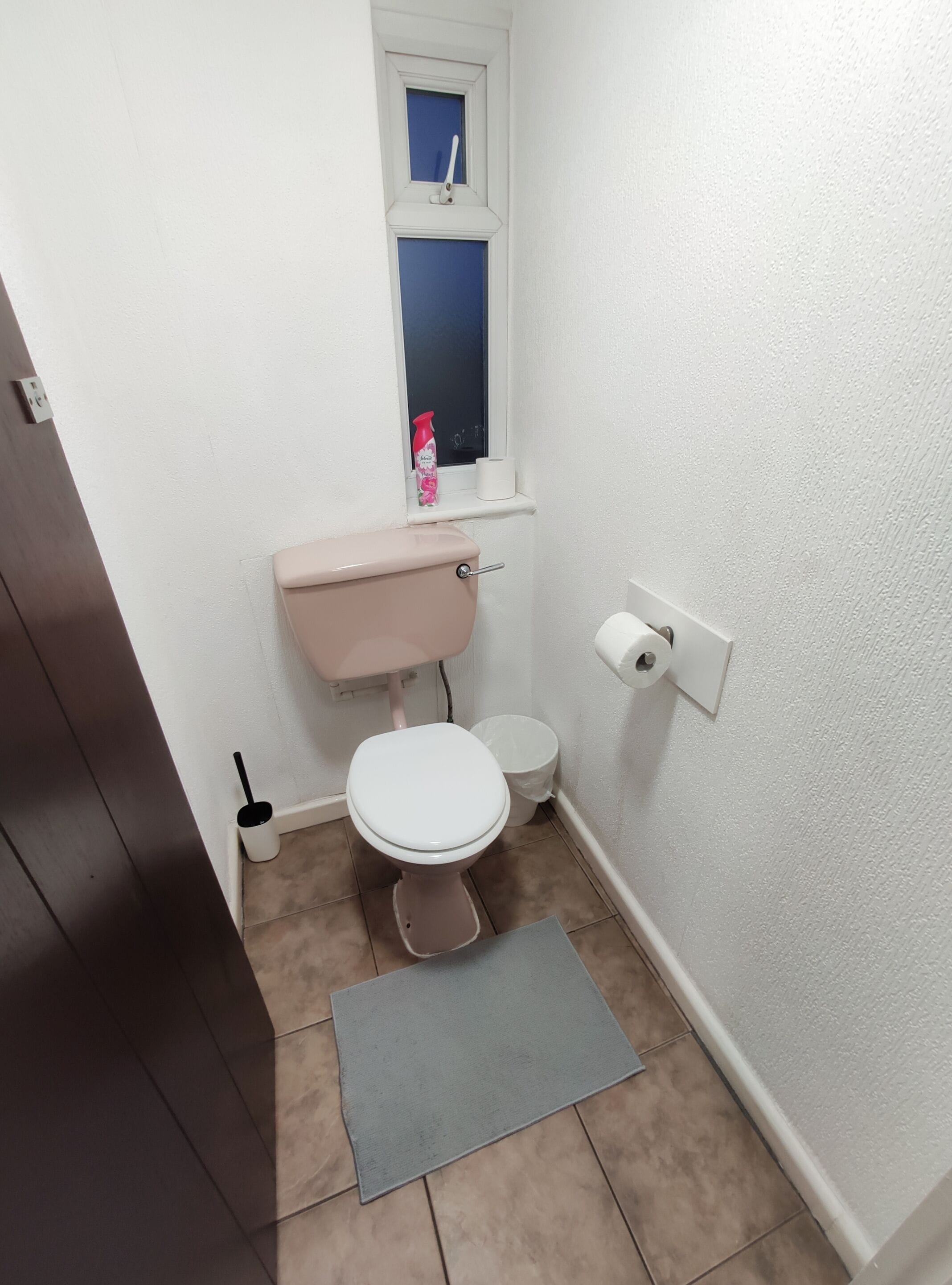 Ett litet, rent badrum med en toalett, en bidé och ett fönster ovanför toaletten.