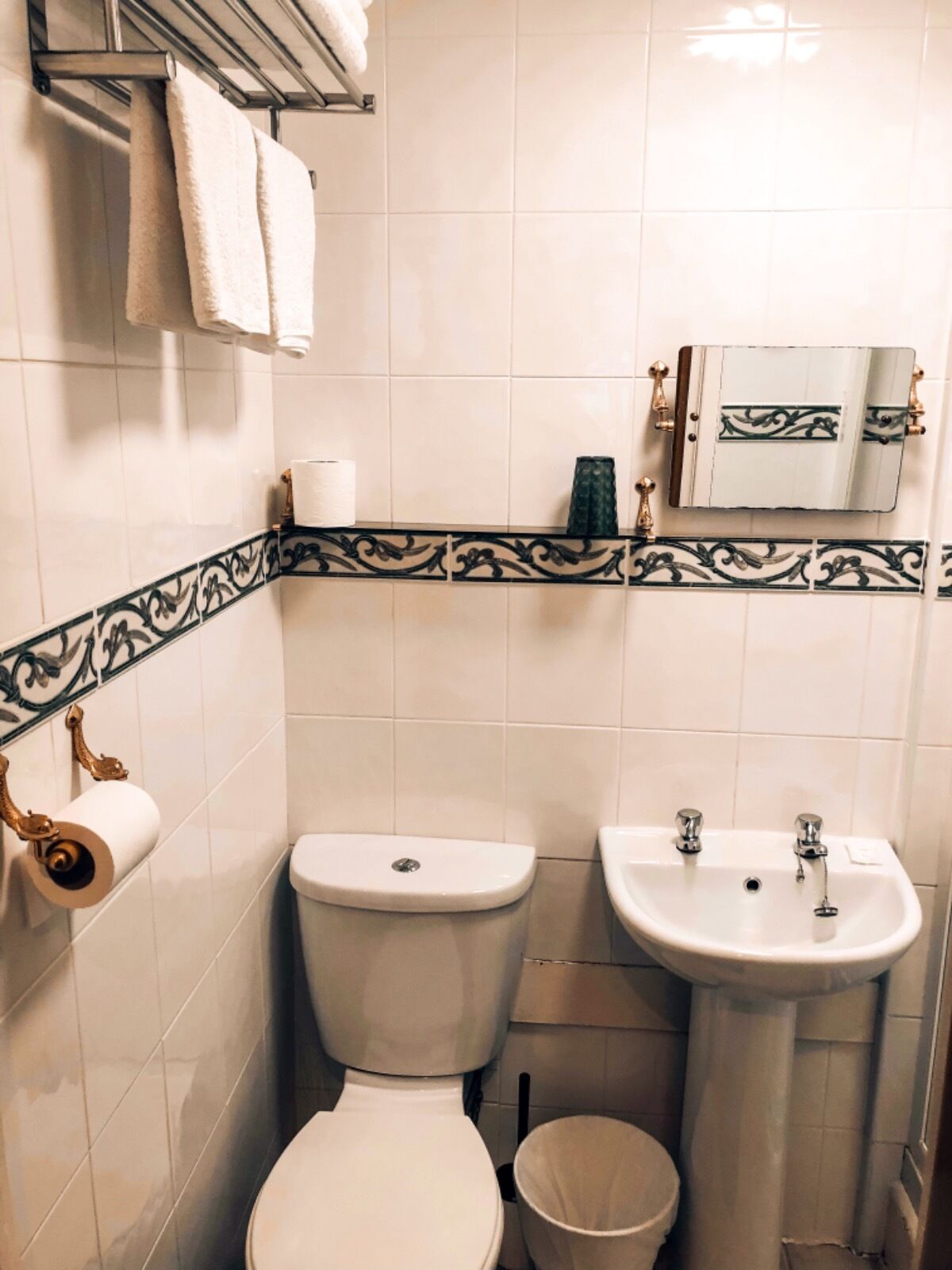 A bathroom with a toilet, sink, and towel rack.