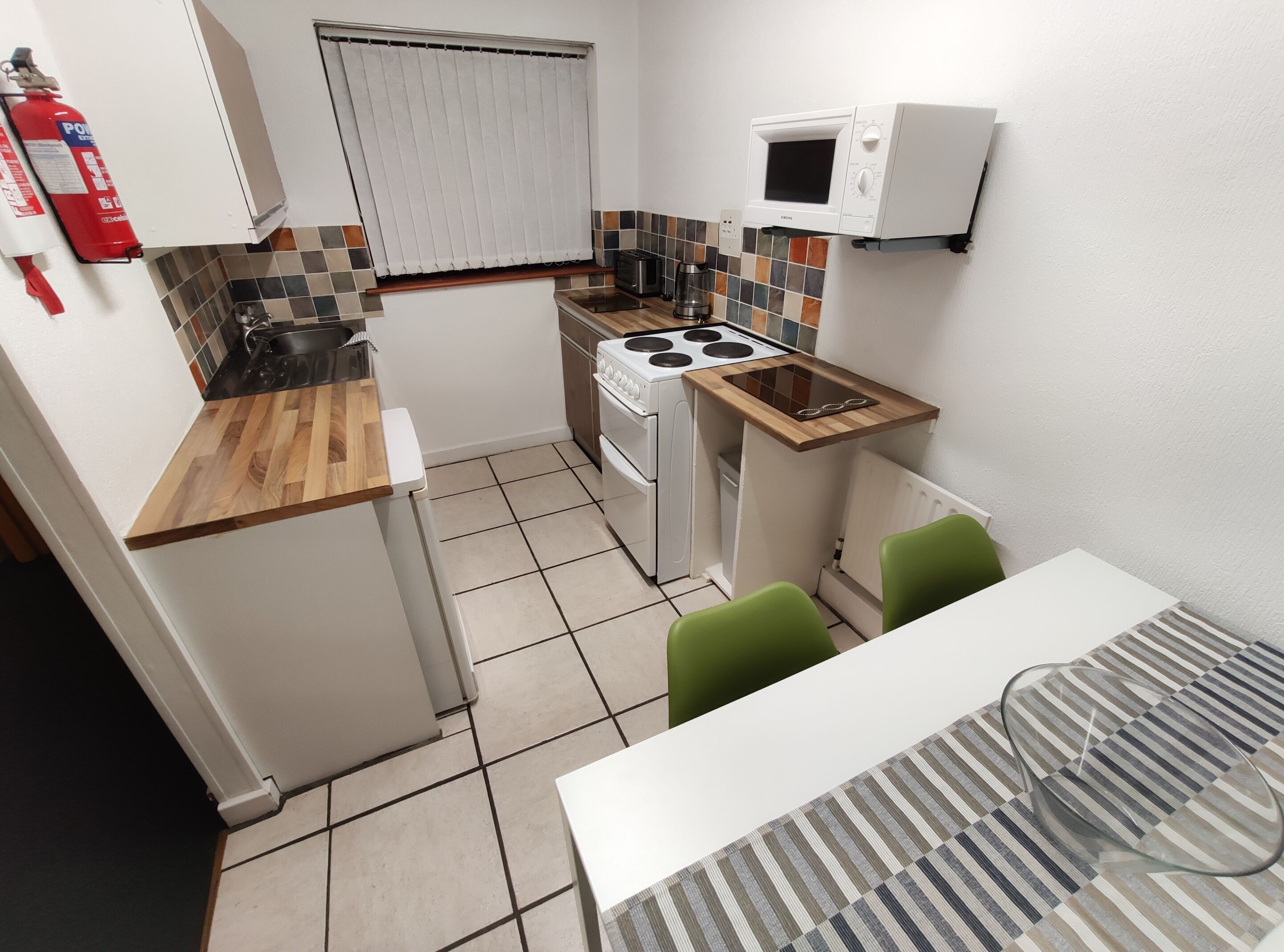 A compact kitchen with a stove, microwave, and a small dining area with a table and chairs.