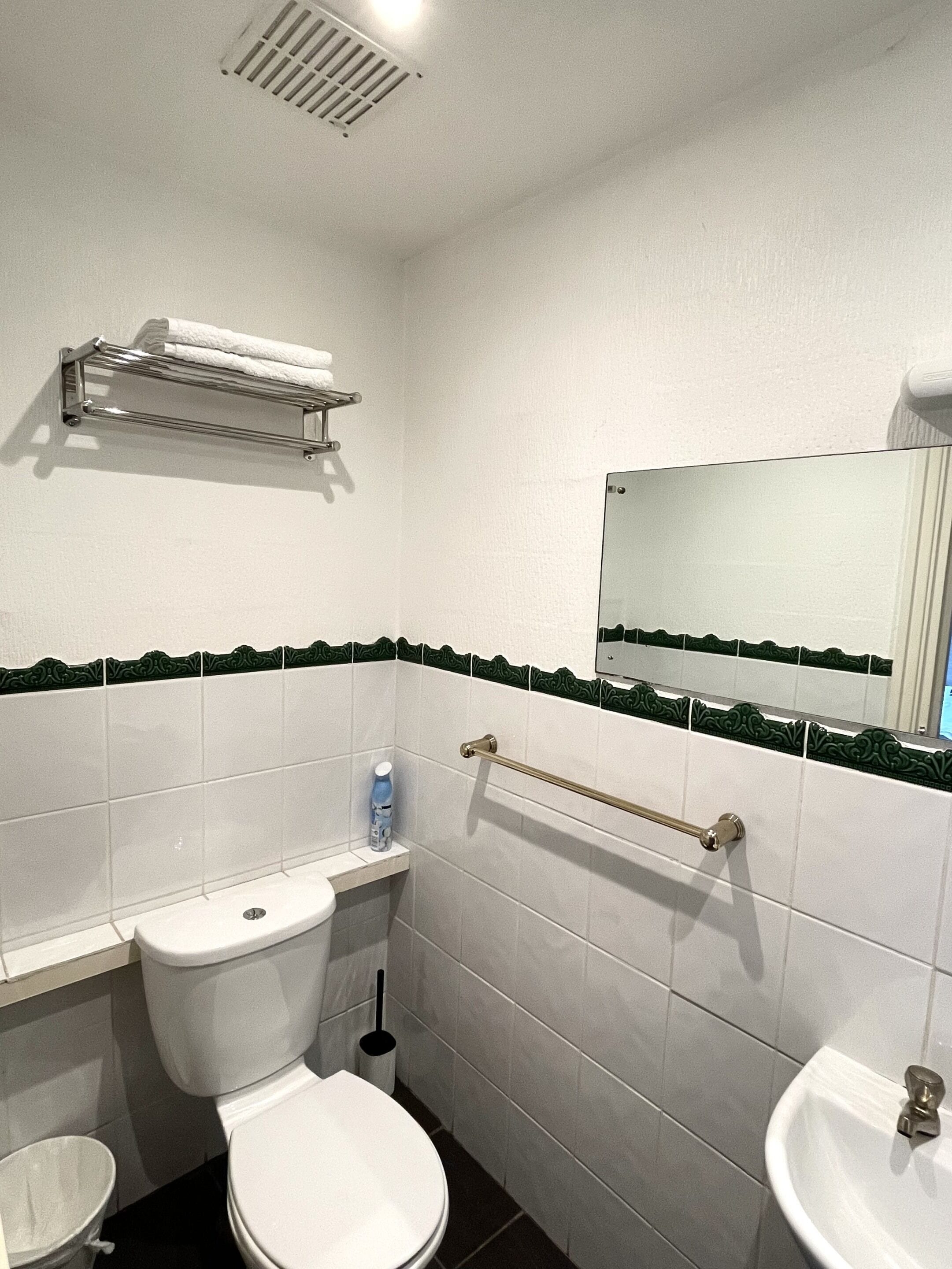 A small, clean bathroom with a toilet, sink, and towel rack.