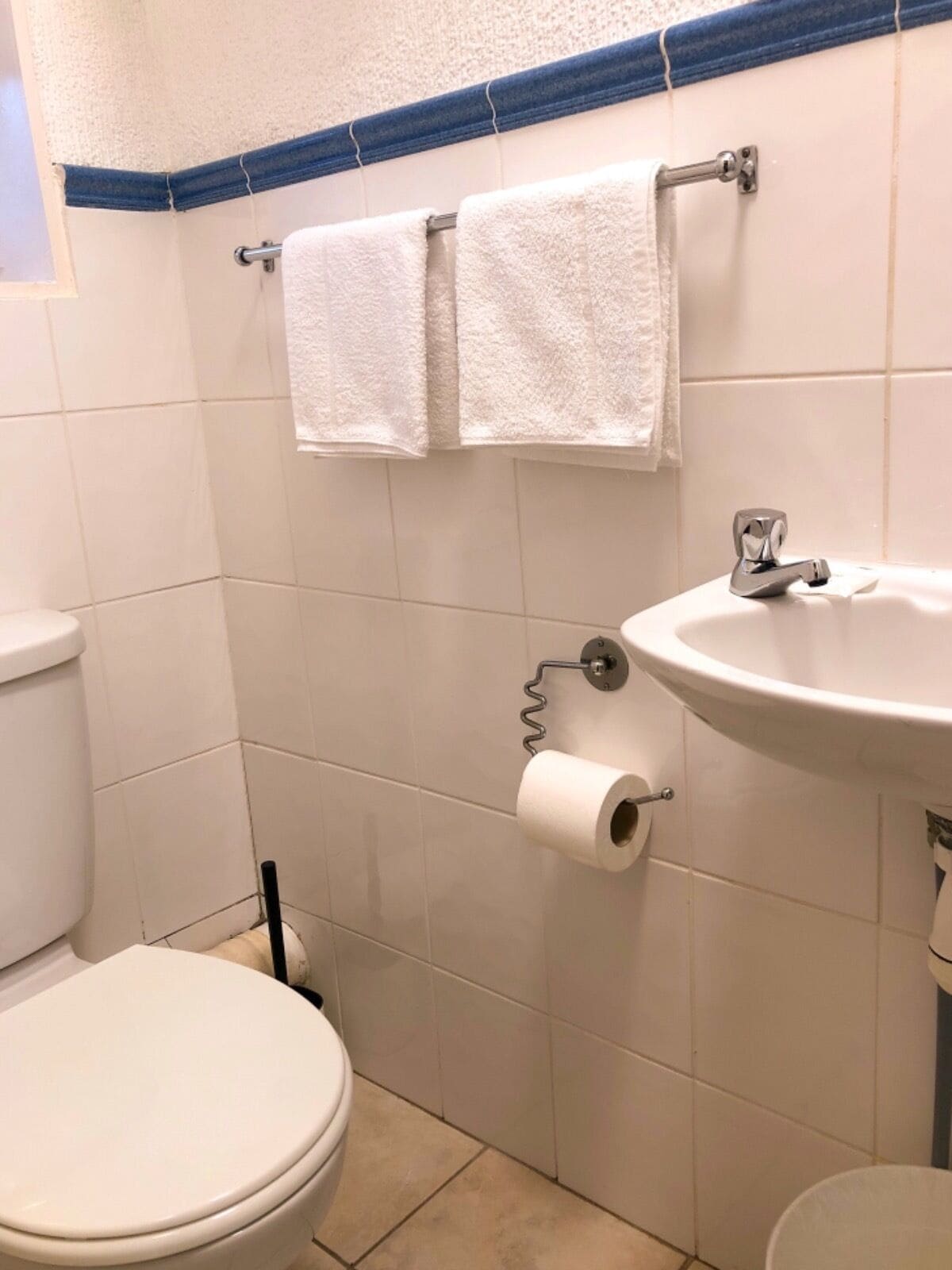 Une salle de bain équipée de toilettes, d’un lavabo et de deux serviettes suspendues à un porte-serviettes.