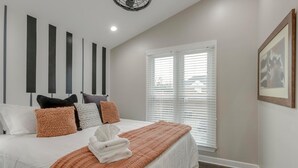 Ein Schlafzimmer mit einem Bett, Kissen, einer Decke, einem Deckenventilator und einem Fenster mit Jalousien.