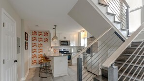 Eine moderne Küche mit weißen Schränken, einer zentralen Kochinsel und einer Edelstahl-Wendeltreppe.
