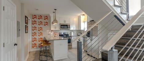 A modern kitchen with white cabinets, a central island, and a stainless steel staircase.