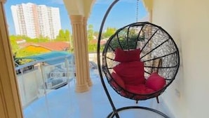 Ein geräumiger Balkon mit einer Hängematte, freie Sicht auf Gebäude und ein Fliesenboden.