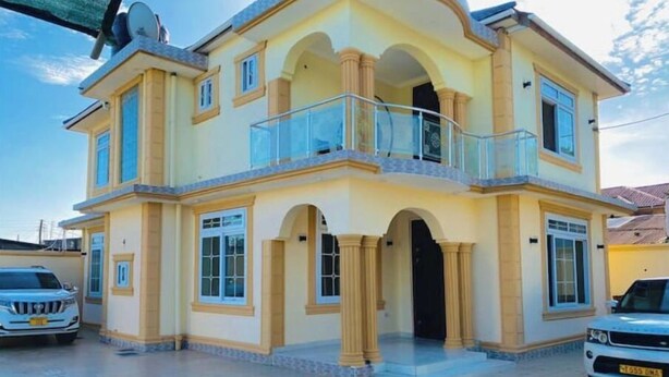 Ein zweigeschossiges Haus mit Balkon, großen Fenstern und einer Auffahrt für zwei Autos.