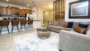A modern kitchen with wooden cabinets, a stainless steel oven, and a bar area with stools. - 4873- Great Family Home near Disney, private pool, Storey Lake (Pet Friendly) (Kissimmee)