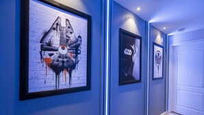 A hallway with framed artwork on the walls, including a Star Wars poster and a space shuttle. - 4873- Great Family Home near Disney, private pool, Storey Lake (Pet Friendly) (Kissimmee)