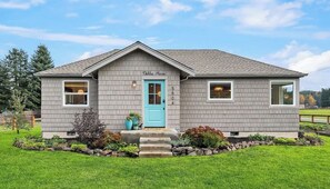 A two-story house with a blue front door, a small porch, and a well-maintained lawn. - Dahlia House of Carnation (Carnation)