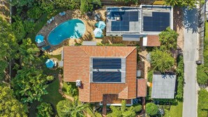 An aerial view of a house with a swimming pool, solar panels, and lush greenery. - Great Amenities, Great Location, Amazing Studio! (West Palm Beach)
