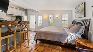 A bedroom with a bed, a desk with two chairs, a television, and a painting on the wall. - Great Amenities, Great Location, Amazing Studio! (West Palm Beach)