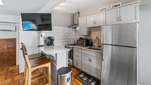 A compact kitchen with a built-in microwave, stove, and stainless steel refrigerator. - Great Amenities, Great Location, Amazing Studio! (West Palm Beach)