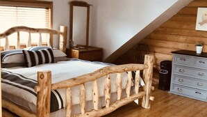 A bedroom with a wooden bed, a dresser, and a mirror.