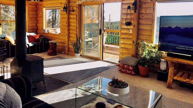 A cozy log cabin interior with a fireplace, a glass coffee table, and a television.