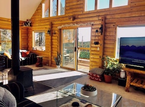 L’intérieur d’un chalet confortable, avec une cheminée, une table basse en verre et un téléviseur.