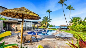 A pool area with lounge chairs, a thatched umbrella, and palm trees. - Double Lanai, Double Ocean Views, all comfort (Lahaina)