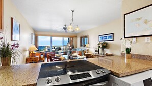 A modern kitchen with a built-in stove, a dishwasher, and a large window overlooking a scenic view. - Double Lanai, Double Ocean Views, all comfort (Lahaina)