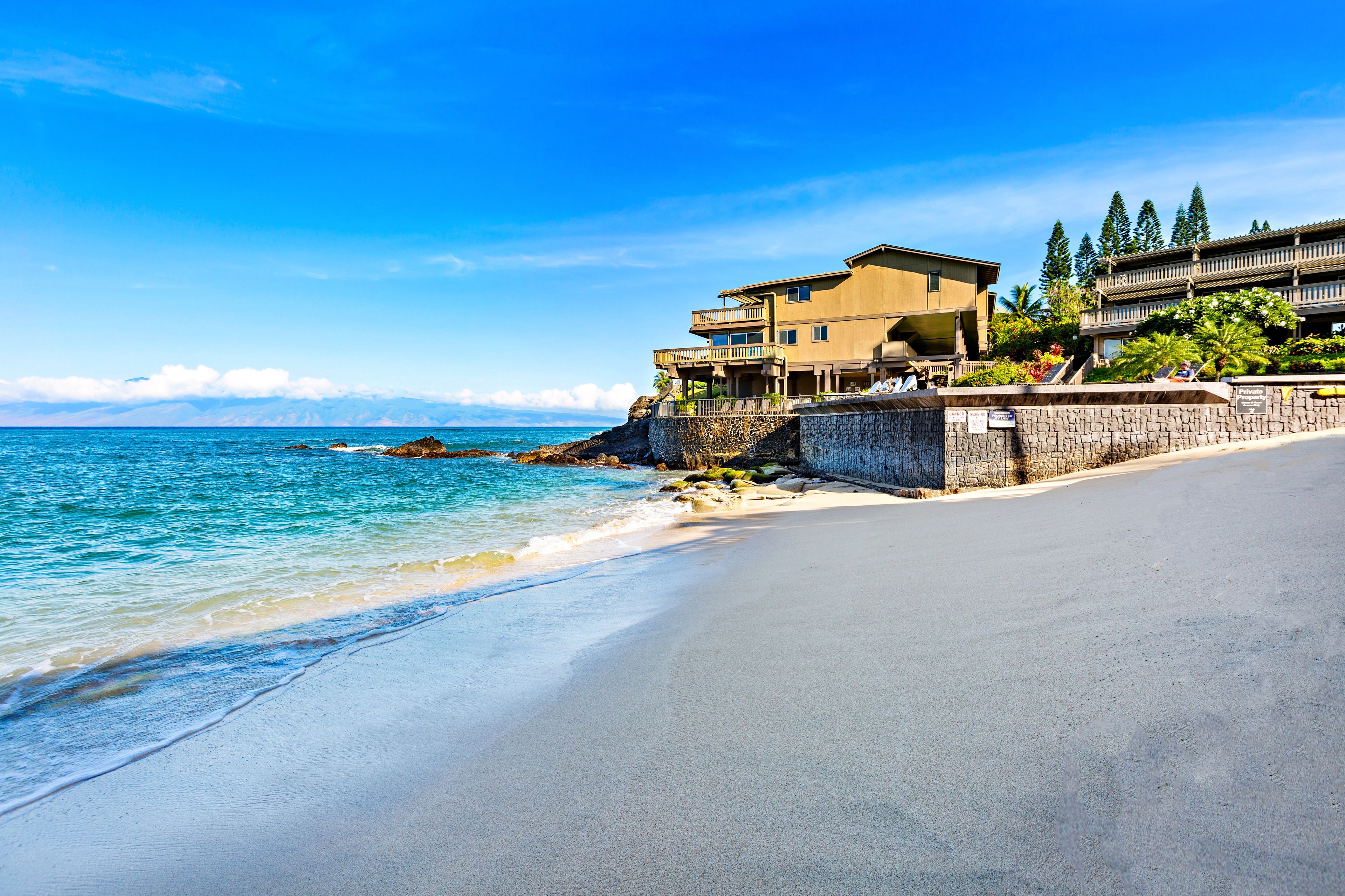 A beachfront property with a stone wall, a wooden deck, and a view of the ocean.