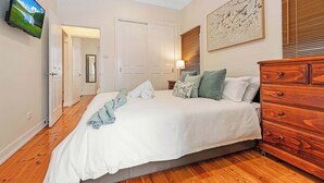Een slaapkamer met een bed, een houten dressoir en een televisie aan de muur.