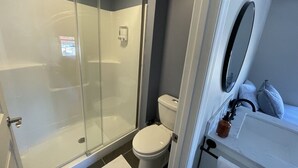 A modern bathroom with a glass-enclosed shower, a toilet, and a sink with a mirror. - Talkin Tackle Outfitter and Lodge (Hixson)