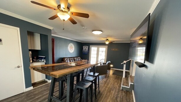 A modern kitchen with a wooden island, bar stools, and a ceiling fan. - Talkin Tackle Outfitter and Lodge (Hixson)