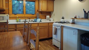 A kitchen with wooden cabinets, a stove, a microwave, and a sink. - Beyersfort next to Cygnet Lake - Sleeps 5, Private Dock w/ Canoe, No Wi-Fi (Condon)