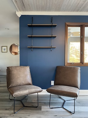 A room with two leather chairs, a blue accent wall, and a window with a view. - Cambridge Retreat (Denver)