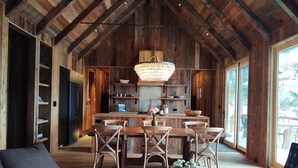 A rustic interior with a wooden dining area, a sofa, and a chandelier.