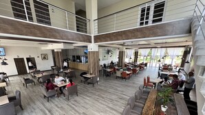 A spacious indoor area with multiple seating arrangements, including tables and sofas, and a central bar area. - Vista Terra (Chiquimula)