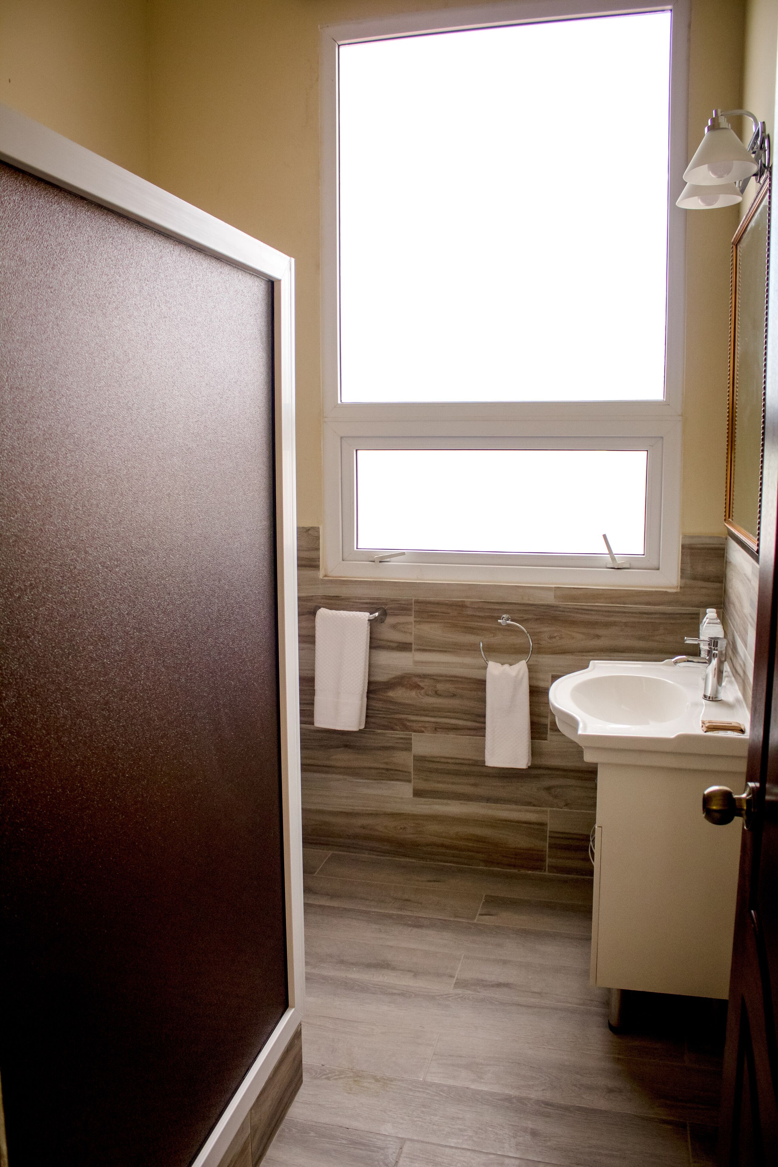 Un baño con ventana, lavamanos y un perchero para toallas.