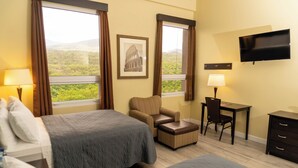 A hotel room with two beds, a desk, a chair, a TV, and a framed picture of a historical building. - Vista Terra (Chiquimula)