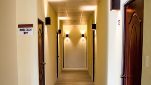 A hallway with wooden flooring, doors on both sides, and wall-mounted light fixtures. - Vista Terra (Chiquimula)