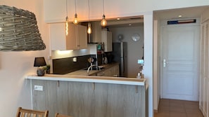 Et moderne køkken med en central ø, hængende lamper og en dekorativ fletning i loftet.