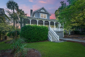 A two-story house with a porch, a staircase, and a well-maintained lawn.