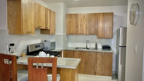 Une cuisine moderne avec des meubles en bois, un réfrigérateur en acier inoxydable, un four encastré et une machine à café.