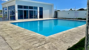 Un bâtiment moderne doté d’une piscine, avec un ciel dégagé et une zone délimitée par une clôture.