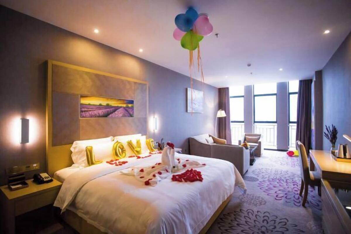 Una habitación de hotel con cama, escritorio, silla y ventana.
