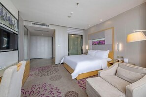 A hotel room with a bed, a sofa, a TV, and a painting on the wall. - Lavande Hotel (Huizhou Yuanzhou) (Boluo)