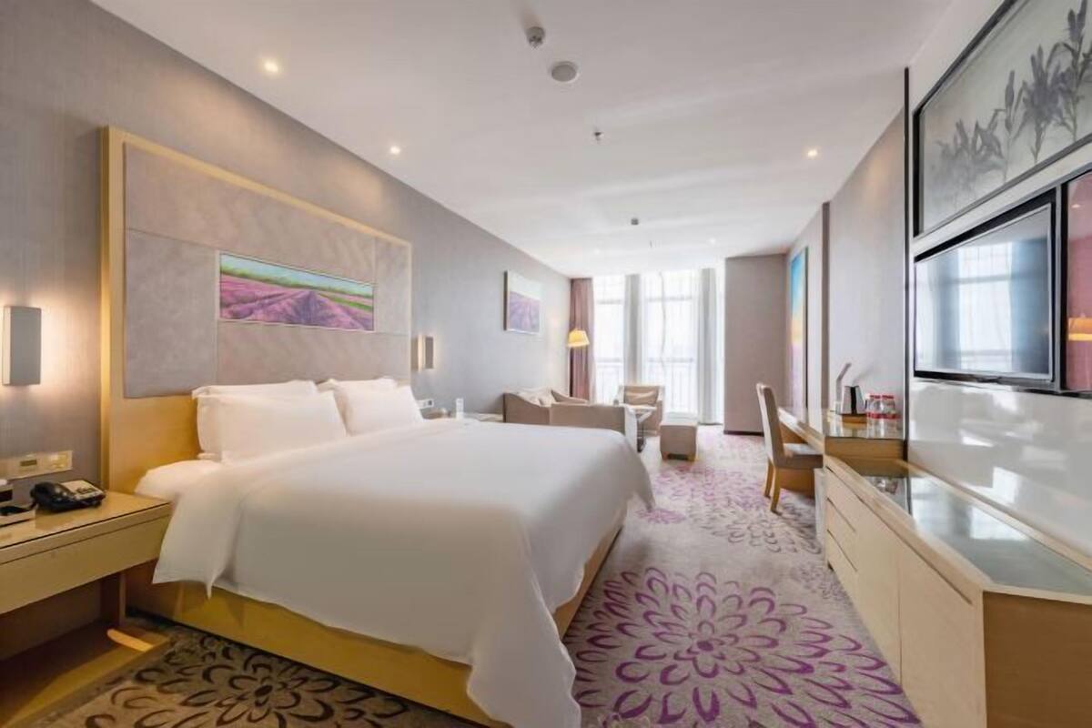 Una habitación de hotel con una cama grande, un escritorio, una silla y un televisor.