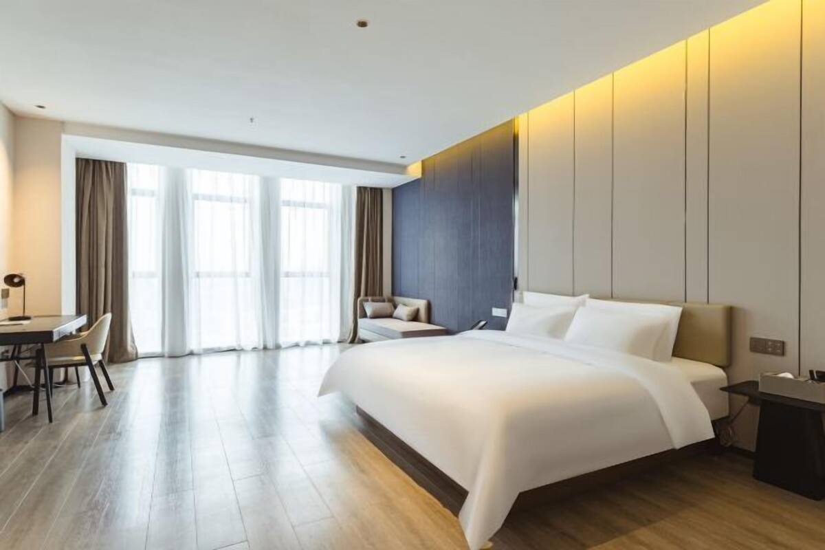 Una habitación de hotel moderna con una cama grande, un escritorio y un sofá.