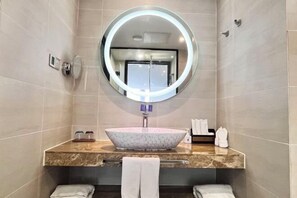 A modern bathroom with a round mirror, a marble sink, and a towel rack. - Lavande Hotel (Huizhou Yuanzhou) (Boluo)