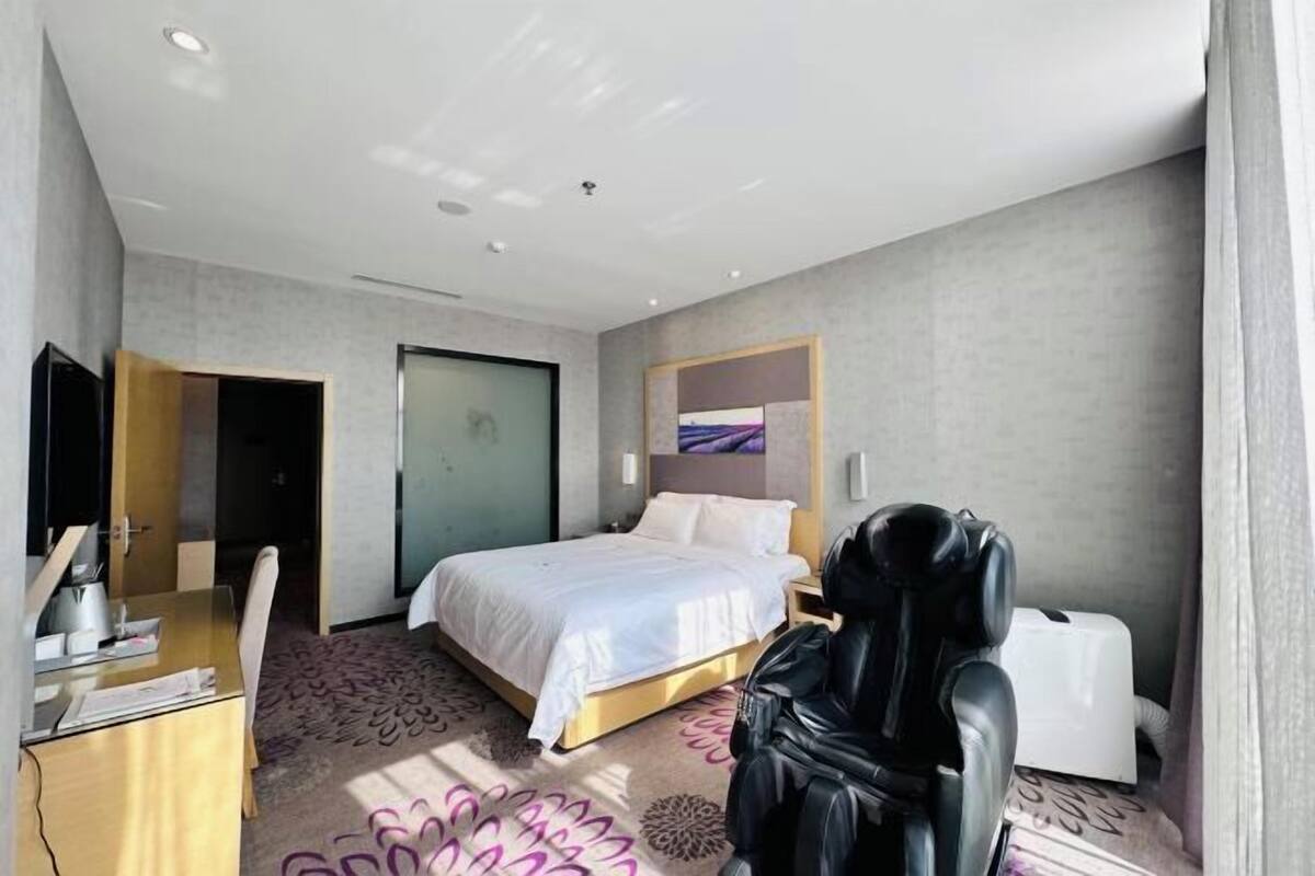 Una habitación de hotel moderna con una cama, una mesita de noche y un escritorio con una silla.