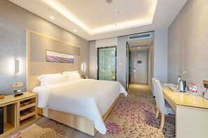 A modern hotel room with a large bed, a desk, and a chair. There is a painting on the wall and a door leading to another room. - Lavande Hotel (Huizhou Yuanzhou) (Boluo)